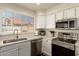 Bright kitchen features stainless steel appliances, white cabinets, and a view of the neighborhood at 7603 W Oraibi Dr, Glendale, AZ 85308