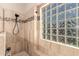 Bright shower with a glass block window, decorative tile accent, and a built-in corner bench at 9559 W Runion Dr, Peoria, AZ 85382
