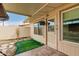 Covered patio with artificial grass, rock ground covering, stepping stones, and exterior door and windows at 11122 W Desert Butte Dr, Sun City, AZ 85351