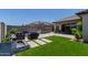 The backyard features a fire pit, an outdoor kitchen, ample seating, and a lush green lawn for relaxing and entertaining at 15276 W Latham St, Goodyear, AZ 85338
