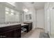 Bathroom with dual sinks, granite counters, vanity area, and a glass-enclosed shower at 15276 W Latham St, Goodyear, AZ 85338
