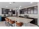 Open kitchen with expansive granite island, stylish barstools, stainless steel appliances, and dark cabinetry at 15276 W Latham St, Goodyear, AZ 85338