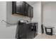 The modern laundry room has a black washer and dryer, upper cabinets, and sleek tile flooring at 15276 W Latham St, Goodyear, AZ 85338