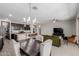 Open-concept living room with dark wood dining table, modern lighting, and kitchen with granite countertops at 15276 W Latham St, Goodyear, AZ 85338