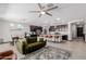 Open concept living area featuring a stylish couch, ceiling fan, kitchen island with seating, and dining area at 15276 W Latham St, Goodyear, AZ 85338