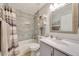 Bright bathroom featuring gray tiled walls, a framed mirror, a single sink vanity, and a shower at 15505 N 135Th Dr, Surprise, AZ 85374