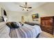 Comfortable bedroom featuring hardwood floors, a ceiling fan, a TV, and an en suite bathroom at 15505 N 135Th Dr, Surprise, AZ 85374