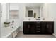 Bright bathroom featuring double sinks, dark cabinets, and a separate tub at 17652 W Fetlock Trl, Surprise, AZ 85387