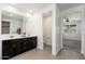 Bright bathroom featuring double sinks, dark cabinets, and an adjoined toilet room at 17652 W Fetlock Trl, Surprise, AZ 85387