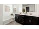 Bright bathroom featuring double sinks, dark cabinets, and a separate tub at 17652 W Fetlock Trl, Surprise, AZ 85387
