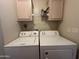 Well-lit laundry room featuring a white washer and dryer with cabinets above for storage at 18026 N Cave Creek Rd # 140, Phoenix, AZ 85032