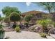 Lush backyard oasis with desert landscaping, mature trees, and a charming stone patio area at 22574 W Moonlight Path, Buckeye, AZ 85326