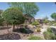 Picturesque backyard with desert landscaping, mature trees, and a cozy stone fire pit feature at 22574 W Moonlight Path, Buckeye, AZ 85326