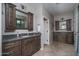 Bathroom with a double sink vanity, dark wood cabinets, granite countertops, and walk-in shower at 22574 W Moonlight Path, Buckeye, AZ 85326