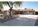 Inviting single-story home with a long driveway, mature trees, neutral tones and a red painted garage at 236 E Minton Dr, Tempe, AZ 85282