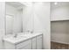 Bright bathroom featuring double sinks, quartz countertop, and a walk-in closet at 25477 W Fraktur Rd, Buckeye, AZ 85326