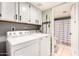 Functional laundry room equipped with modern washer and dryer units, white cabinetry, and easy access to the bathroom at 26 E Coral Gables Dr, Phoenix, AZ 85022