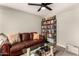 Comfortable living room with a plush leather couch, a glass coffee table, and a full bookshelf, perfect for relaxation at 26 E Coral Gables Dr, Phoenix, AZ 85022