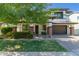 Charming two-story home with brick accents, covered porch, dark gray garage doors, and lush green grass at 4167 E Sierra Madre Ave, Gilbert, AZ 85296