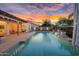 A backyard pool with waterfall features surrounded by lush landscaping and outdoor seating at sunset at 4206 E Blue Ridge Pl, Chandler, AZ 85249