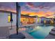 A luxurious backyard pool surrounded by a brick patio and with a covered outdoor living space at sunset at 4206 E Blue Ridge Pl, Chandler, AZ 85249