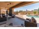 An expansive backyard featuring a pool with a rock waterfall, a raised patio, and lounge furniture at 4418 W Yoosooni Dr, New River, AZ 85087