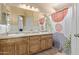 Bathroom featuring dual sinks, a large mirror, vanity lighting and shower tub with colorful shower curtain at 5018 W Wikieup Ln, Glendale, AZ 85308