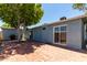 Spacious backyard with a brick patio, mature tree, and blue exterior at 8042 W Mariposa Dr, Phoenix, AZ 85033