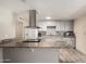 Well-lit kitchen with an island cooktop, neutral countertops, grey cabinets, and stainless steel range hood at 8042 W Mariposa Dr, Phoenix, AZ 85033