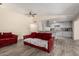 Open living room view showcasing red sofas and adjacent kitchen with gray cabinets and stainless steel appliances at 8042 W Mariposa Dr, Phoenix, AZ 85033