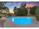 An inviting backyard pool glistening under a colorful dusk sky, surrounded by lush greenery for ultimate privacy at 8604 S Oak St, Tempe, AZ 85284