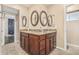 Bathroom featuring a granite topped vanity with dual sinks, framed mirrors, neutral colors, and tile flooring at 8620 E Sells Dr, Scottsdale, AZ 85251