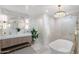 Bright bathroom featuring dual sinks, luxurious tub and shower with elegant gold fixtures and stylish chandelier lighting at 908 W Pershing Ave, Phoenix, AZ 85029