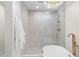 Modern bathroom featuring tiled shower, luxurious tub, and elegant gold fixtures under stylish chandelier lighting at 908 W Pershing Ave, Phoenix, AZ 85029