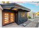 The home's exterior with double doors, dark wood siding, gravel landscaping, and modern design at 908 W Pershing Ave, Phoenix, AZ 85029