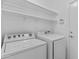 Functional laundry room with white washer and dryer, overhead shelving, and easy access to the outdoors at 10727 E El Moro Ave, Mesa, AZ 85208