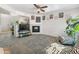 Cozy living room features neutral carpet, a corner fireplace, ceiling fan, and decorative Gathering artwork at 1374 E 10Th Pl, Casa Grande, AZ 85122