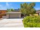 Exterior view featuring a two-car garage, landscaped yard, and mature trees surrounding the home at 1419 E Las Palmaritas Dr, Phoenix, AZ 85020