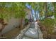 Exterior view featuring a concrete walkway and steps leading to the side entrance surrounded by mature trees and landscaping at 1419 E Las Palmaritas Dr, Phoenix, AZ 85020