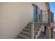 Stairway leading to an upper-level entrance featuring a blue door and a wooden railing and textured stucco siding at 1419 E Las Palmaritas Dr, Phoenix, AZ 85020