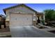 A well-lit garage door is featured in this exterior view of this one story, desert home, with xeriscaping at 14360 W Pershing St, Surprise, AZ 85379