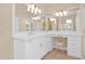 Well-lit vanity area featuring a double vanity with white cabinets, a large mirror, and seating at 1940 N Stevens Cir, Mesa, AZ 85205