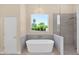 Modern bathroom featuring a freestanding tub, glass enclosed shower, and window with natural light at 1940 N Stevens Cir, Mesa, AZ 85205
