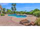 Backyard pool with waterfall feature, diving board, and lush landscaping under a clear blue sky at 1940 N Stevens Cir, Mesa, AZ 85205