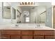 Bathroom featuring double sinks, a large mirror with lighting, and a walk-in shower at 20632 N 103Rd Ave, Peoria, AZ 85382