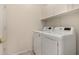 Well-lit laundry room featuring white front-loading washer and dryer, plus overhead storage cabinets at 20632 N 103Rd Ave, Peoria, AZ 85382