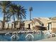Community pool with palm trees, lounge seating and residents enjoying water aerobics on a clear, sunny day at 20632 N 103Rd Ave, Peoria, AZ 85382