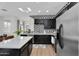Bright kitchen with stainless steel appliances, black cabinets, geometric backsplash, and island with quartz countertop at 240 W Juniper Ave # 1020, Gilbert, AZ 85233
