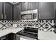 Updated kitchen features stainless steel appliances, black cabinetry with gold hardware, and geometric backsplash at 240 W Juniper Ave # 1020, Gilbert, AZ 85233