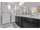 A modern bathroom with double sinks, dark wood cabinets, and a walk-in shower with glass doors at 2625 S Peppertree Dr # 101, Gilbert, AZ 85295
